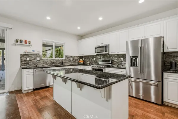 a kitchen with stainless steel appliances granite countertop a refrigerator a sink a stove a microwave and island