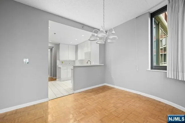 an empty room with chandelier fan and windows
