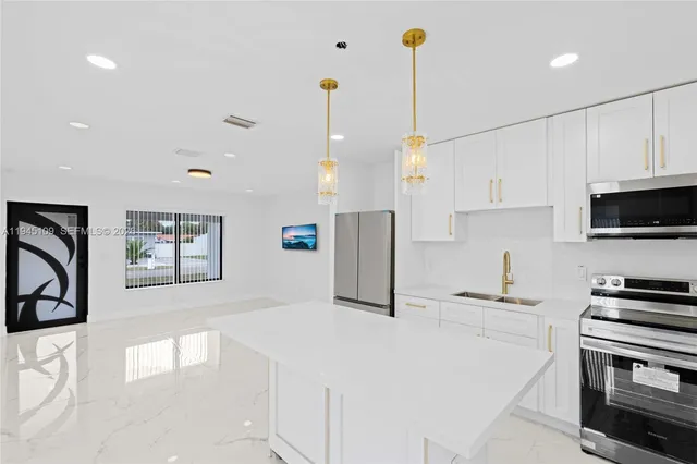 a kitchen with stainless steel appliances kitchen island granite countertop a stove a sink a microwave and a refrigerator