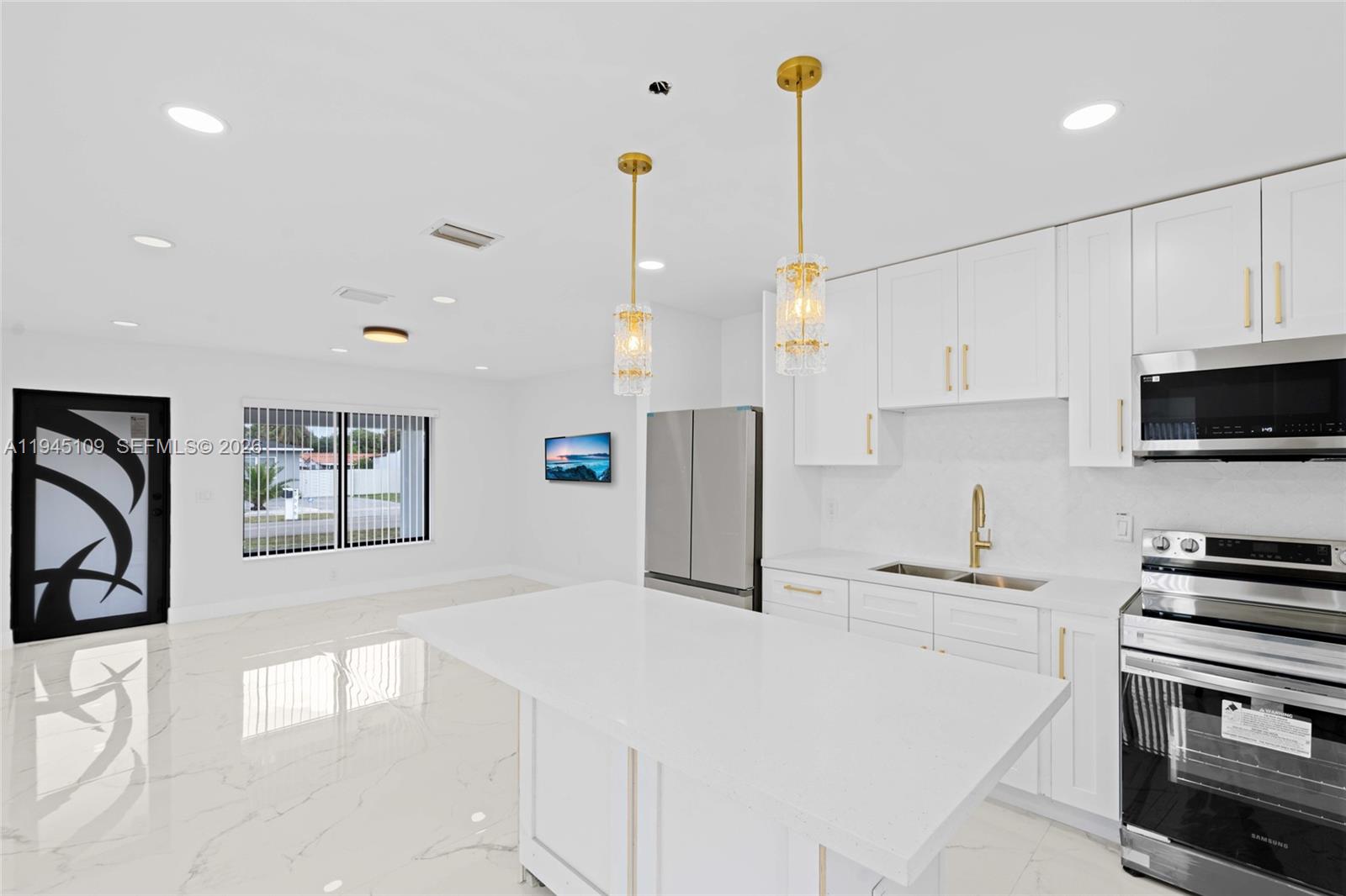 3030 Northwest 99th Street Miami, FL 33147 - Photo 5 of 27 a kitchen with stainless steel appliances kitchen island granite countertop a stove a sink a microwave and a refrigerator