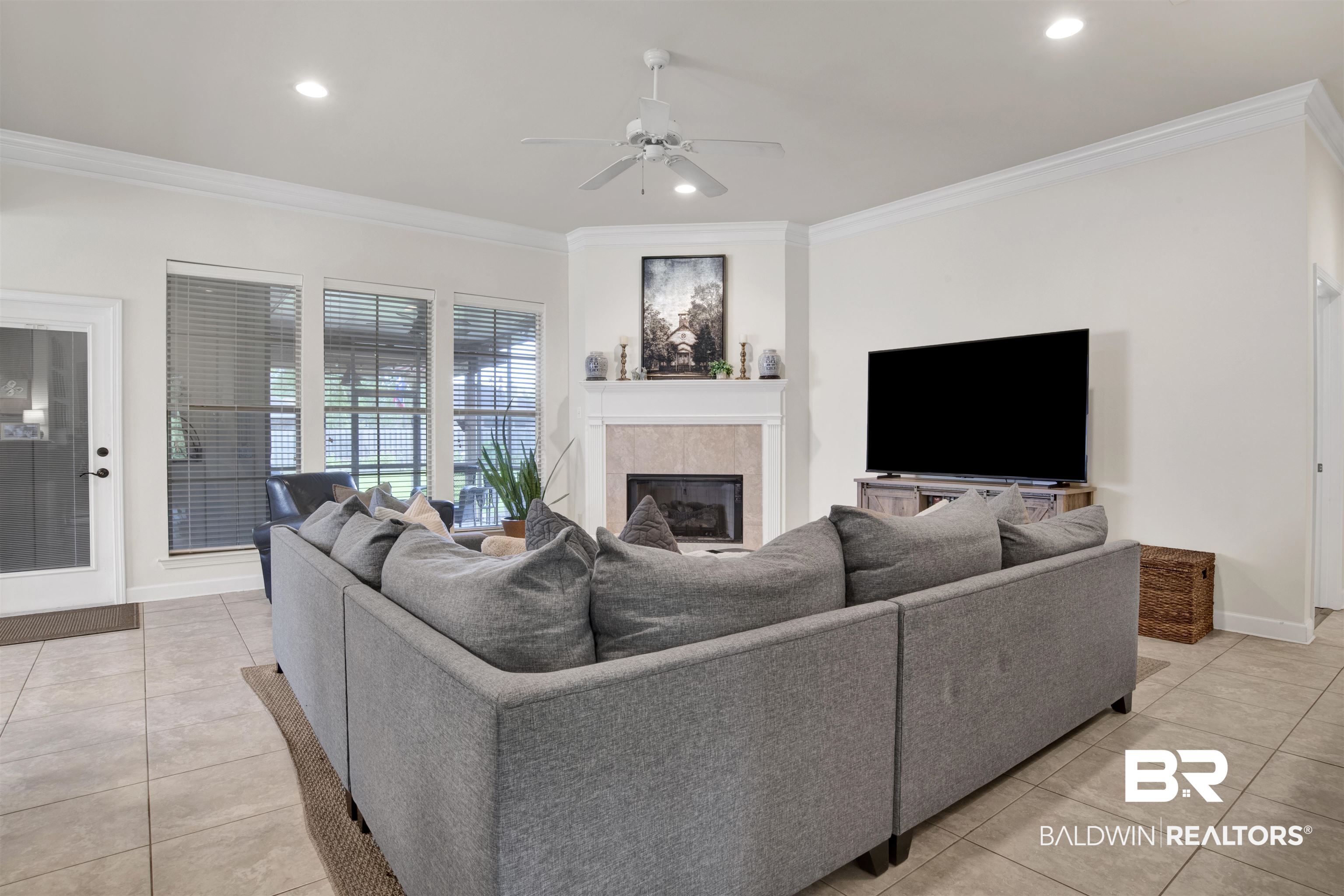 10368 Gayfer Rd Extension Fairhope, AL 36532 - Photo 4 of 43 Living area featuring ceramic tile flooring, a corner fireplace with a tiled surround and mantel, and crown molding