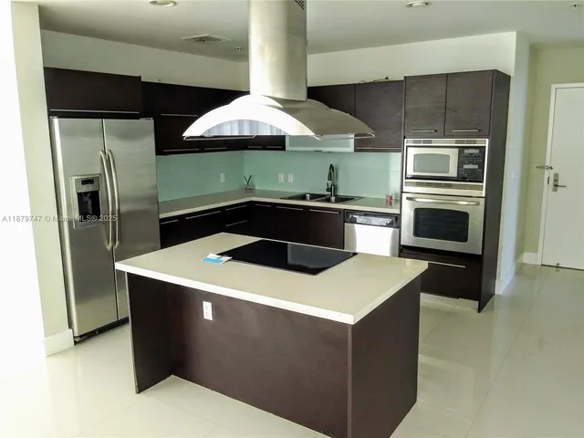 a kitchen with stainless steel appliances kitchen island a sink and a refrigerator