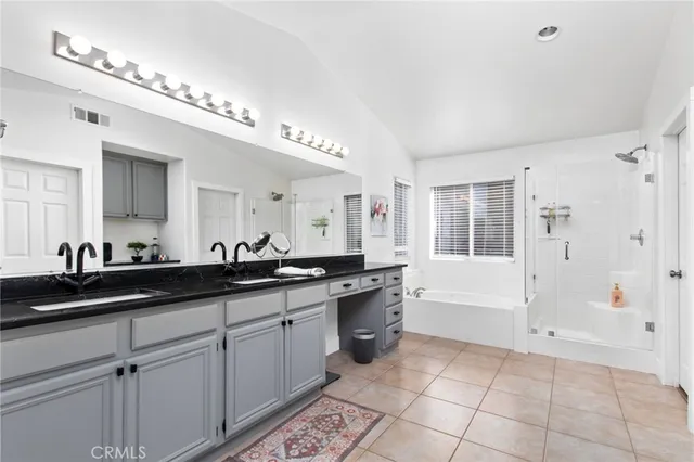 a large bathroom with a granite countertop double vanity sink a mirror and a bathtub