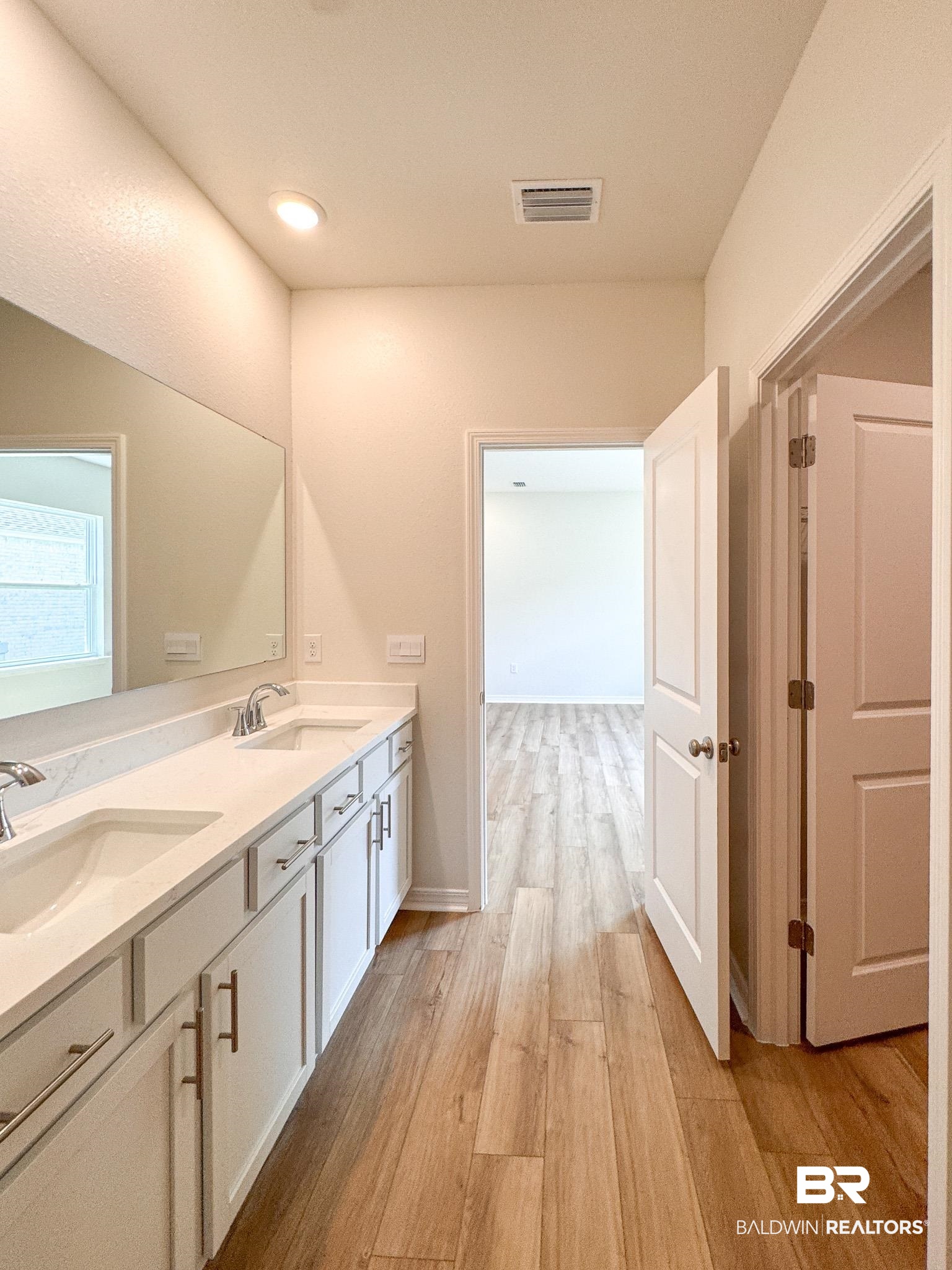 18151 Kent Circle Foley, AL 36535 - Photo 19 of 25 Bathroom featuring a double vanity with white cabinetry, integrated sinks, chrome fixtures, and a large wall-mounted mirror