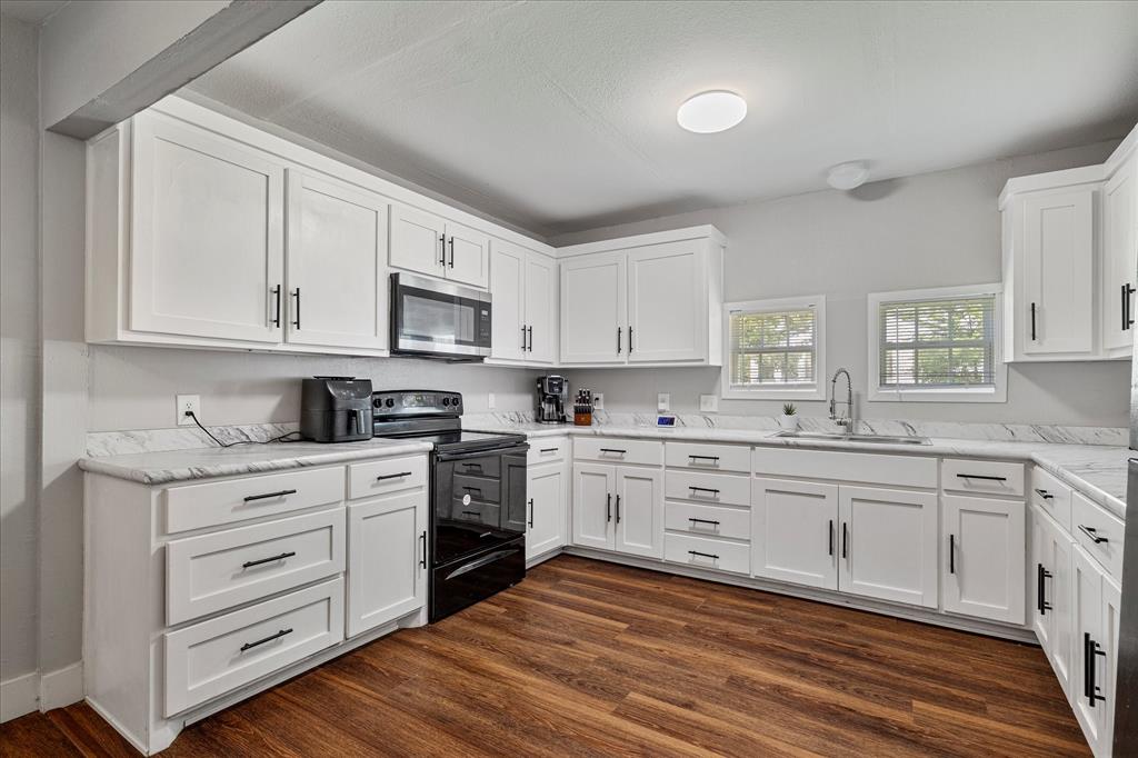 25 West Parnell Street Denison, TX 75020 - Photo 7 of 16 a kitchen with granite countertop white cabinets and white appliances
