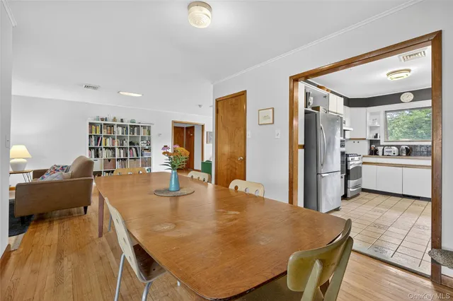 a kitchen with stainless steel appliances granite countertop a refrigerator a stove and a dining table with wooden floor