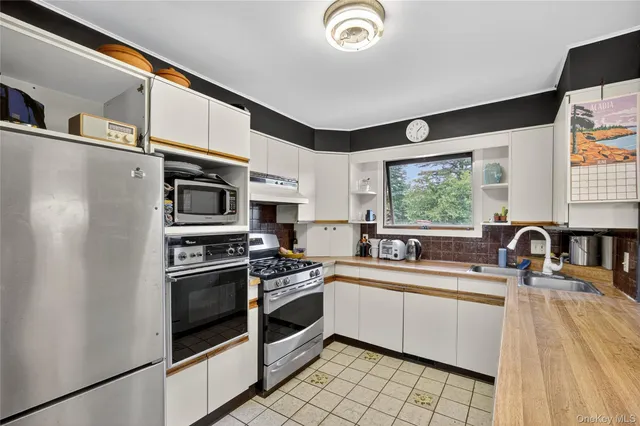 a kitchen with stainless steel appliances a sink cabinets and a window
