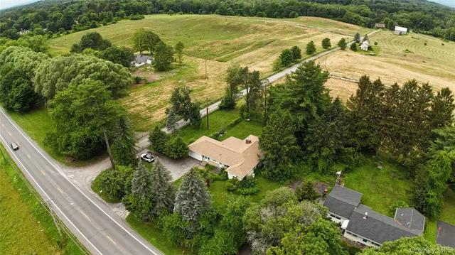 an aerial view of a residential houses with outdoor space and trees all around
