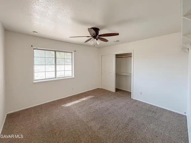 an empty room with chandelier fan and windows