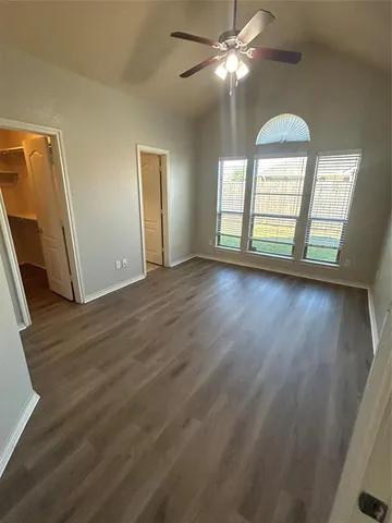 a view of empty room with wooden floor and fan