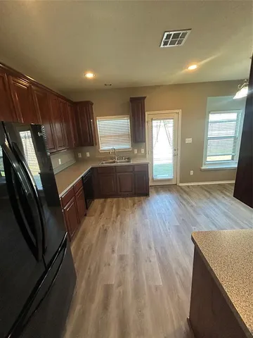 a large kitchen with a sink a window and stainless steel appliances