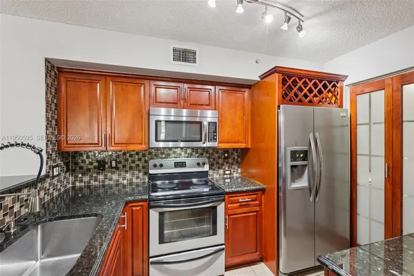 a kitchen with stainless steel appliances granite countertop a refrigerator and a stove top oven
