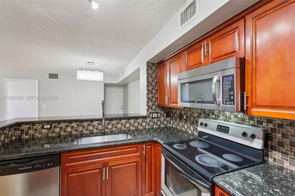 a kitchen with granite countertop a stove sink and cabinets
