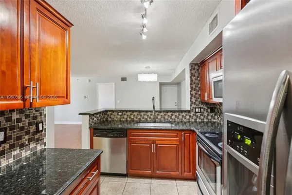 a kitchen with stainless steel appliances granite countertop a stove a sink and a microwave