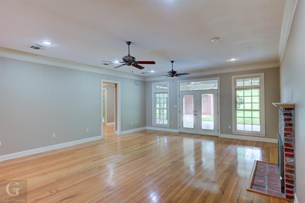 1212 WPA Road Homer, LA 71040 - Photo 12 of 35 Unfurnished living room with crown molding, baseboards, light wood finished floors, a brick fireplace, and ceiling fan