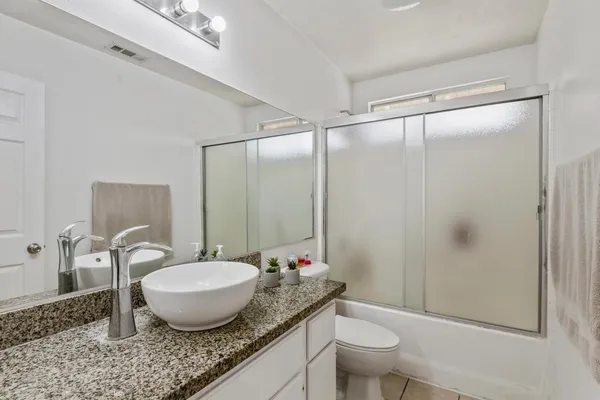 a bathroom with a granite countertop sink toilet a mirror and shower