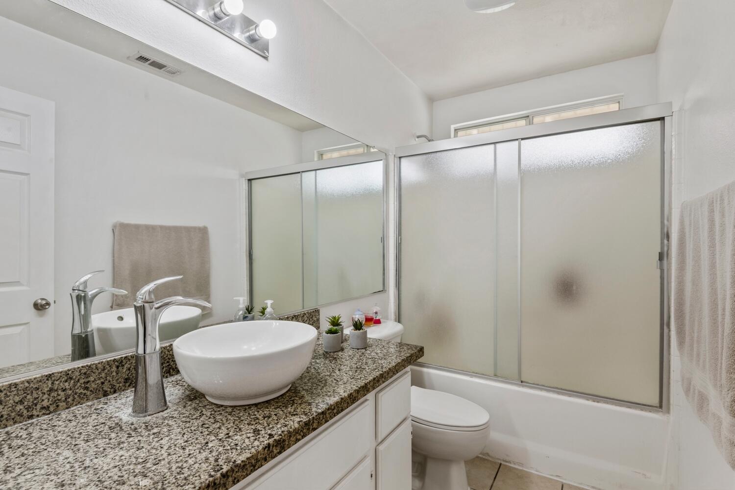 13702 Inaja Street Desert Hot Springs, CA 92240 - Photo 15 of 19 a bathroom with a granite countertop sink toilet a mirror and shower