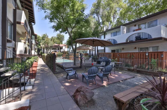 a view of a patio with table and chairs under an umbrella with wooden fence