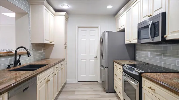 a kitchen with stainless steel appliances granite countertop a sink stove and refrigerator