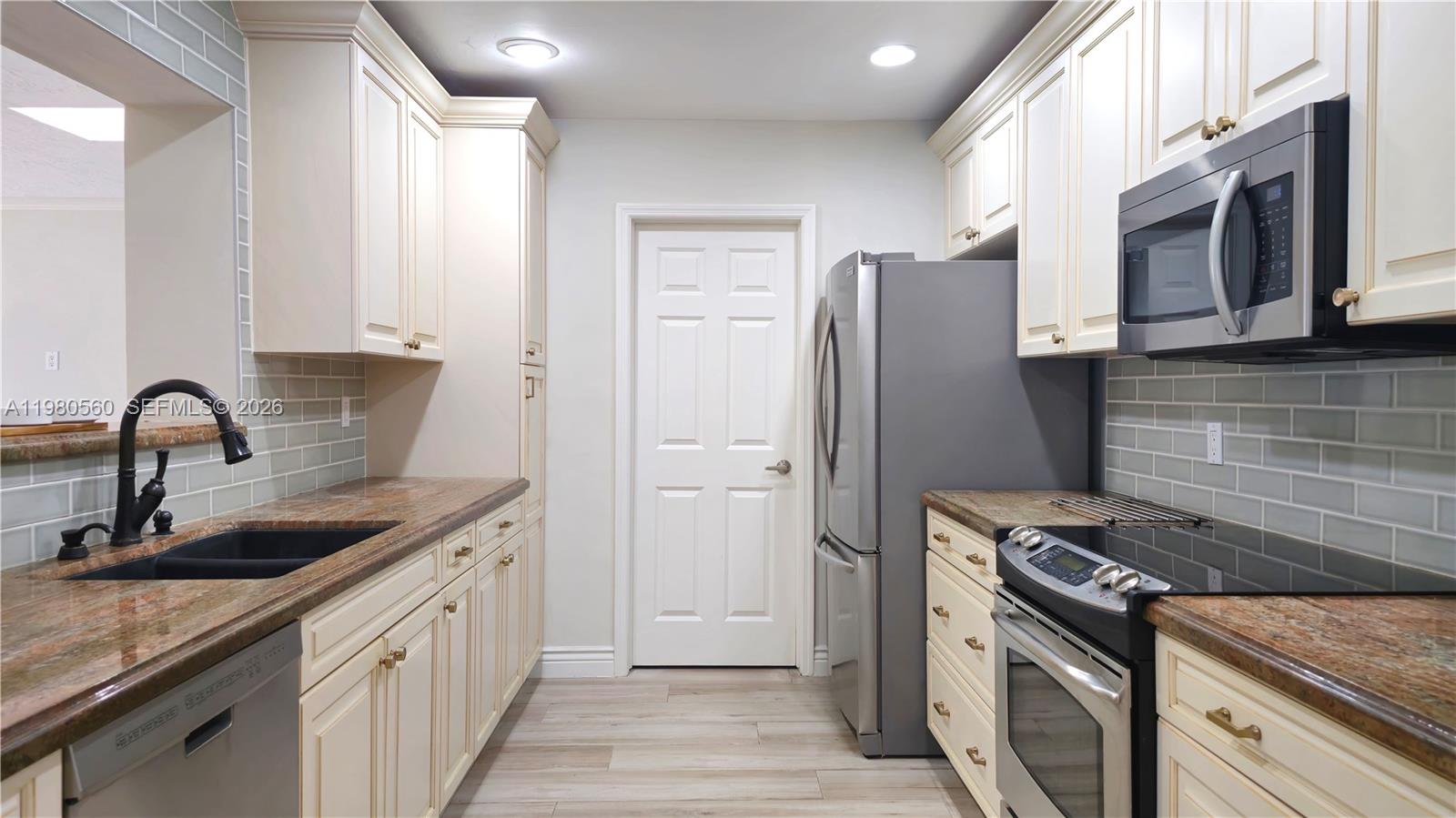 909 Southwest 9th Avenue Boca Raton, FL 33486 - Photo 4 of 18 a kitchen with stainless steel appliances granite countertop a sink stove and refrigerator