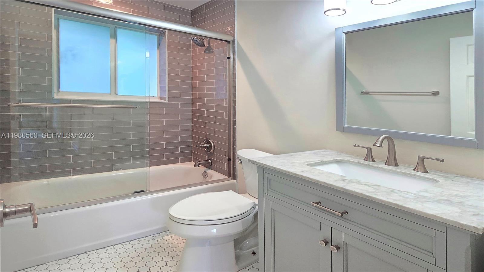 909 Southwest 9th Avenue Boca Raton, FL 33486 - Photo 9 of 18 a bathroom with a granite countertop toilet a sink and bathtub