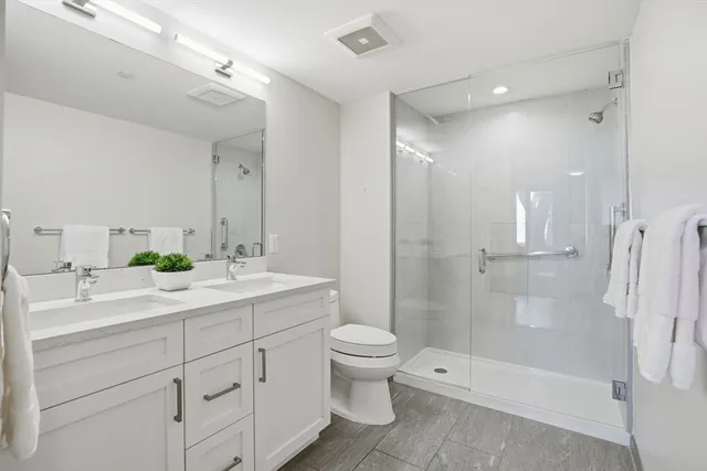 a bathroom with a double vanity sink toilet mirror and shower