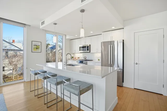 a kitchen with stainless steel appliances granite countertop a refrigerator a stove top oven a sink dishwasher and white cabinets with wooden floor