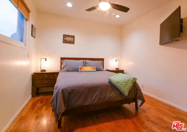 a bedroom with a bed and a flat tv screen on dresser