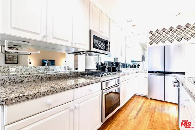 a kitchen with granite countertop a sink a stove and refrigerator