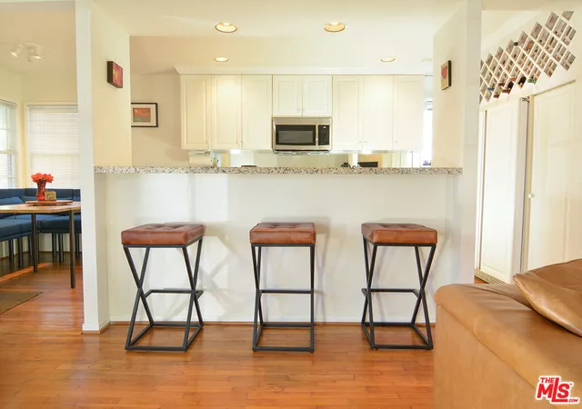 a kitchen with stainless steel appliances granite countertop a table chairs microwave and sink