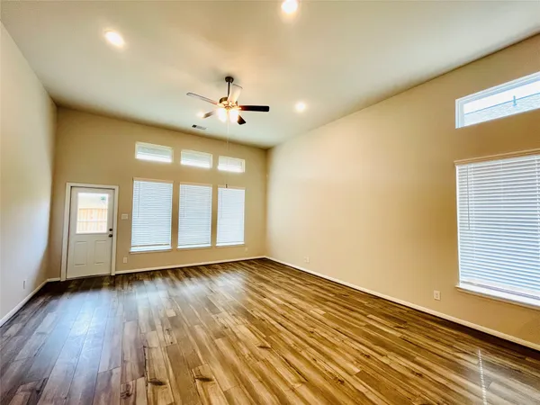 a view of an empty room with a window and wooden floor