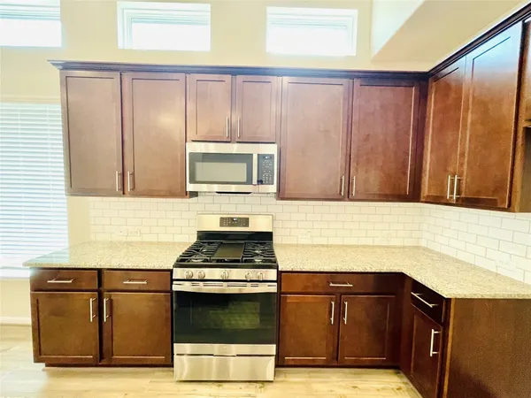 a kitchen with granite countertop wooden cabinets and a stove top oven