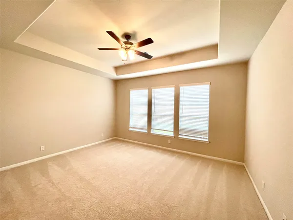 a view of an empty room with chandelier fan and a window