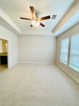 an empty room with ceiling fan and windows