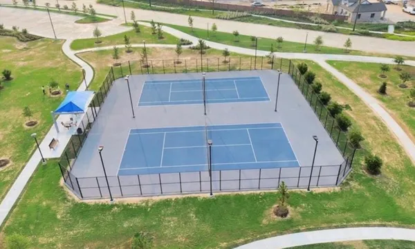 aerial view of a tennis ground and a cars park side of the road
