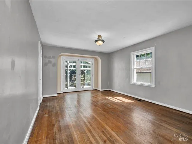 a view of an empty room with wooden floor and a window