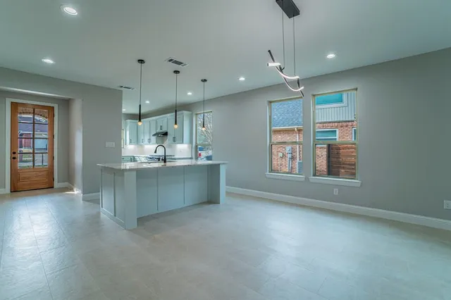a kitchen with kitchen island a sink a stove a dining table and chairs