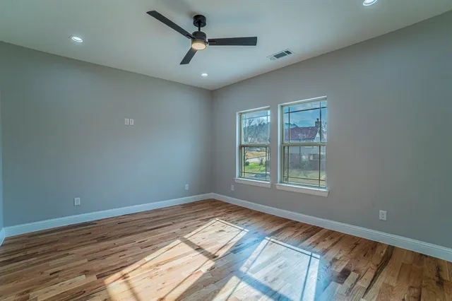 a view of empty room with wooden floor and fan