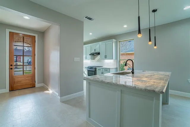 a kitchen with kitchen island a sink a stove and a refrigerator