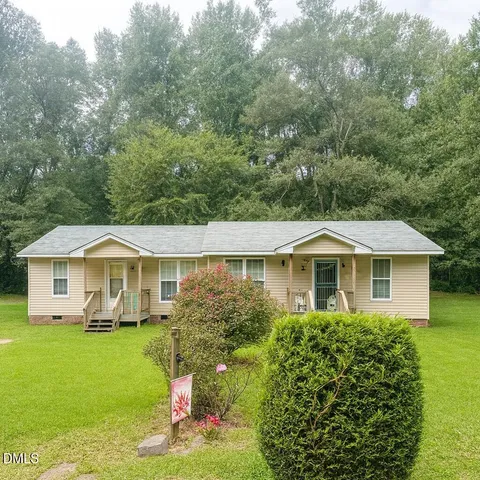 a front view of a house with a garden and trees