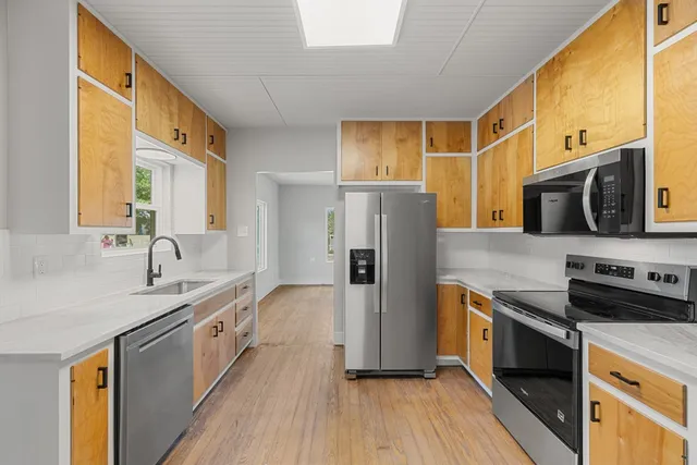 a kitchen with stainless steel appliances a sink cabinets and a wooden floor