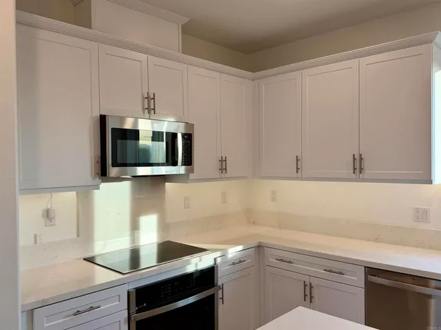 a kitchen with kitchen island granite countertop a sink cabinets and stainless steel appliances