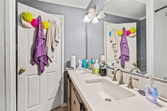 a bathroom with a sink a mirror and painting on the wall