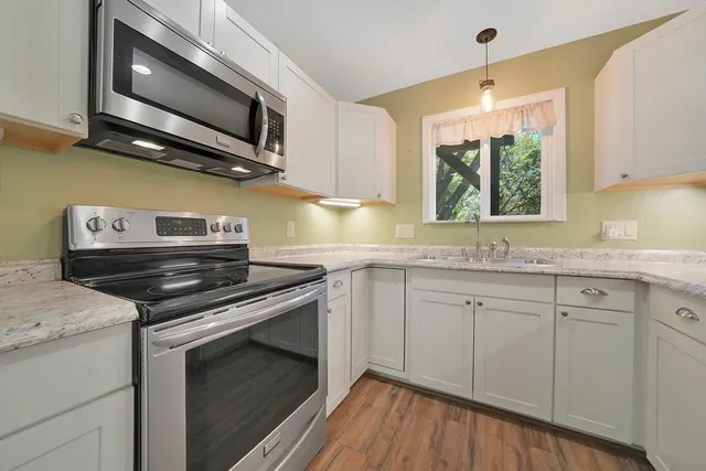 a kitchen with stainless steel appliances white cabinets granite counter tops and a window
