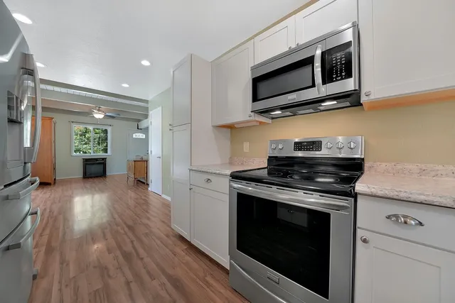 a kitchen with stainless steel appliances a stove a microwave oven cabinets and wooden floor