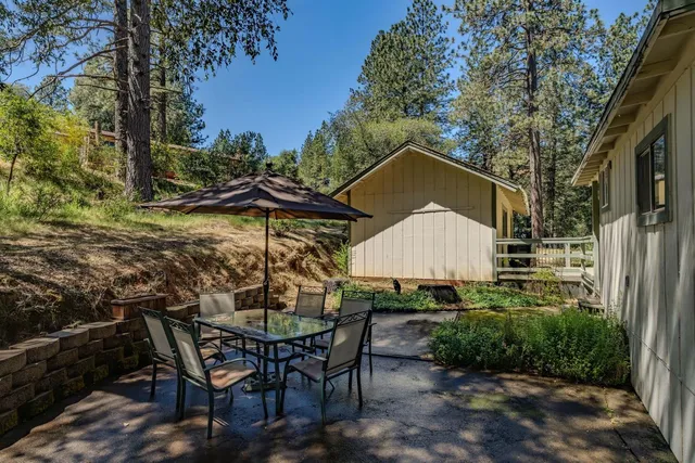 a backyard of a house with table and chairs under an umbrella
