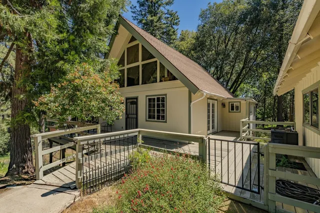 a front view of house with deck area and trees