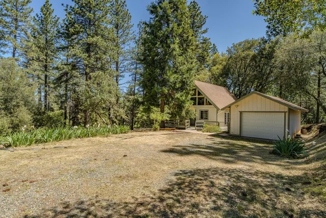 a view of a house with a yard and large trees