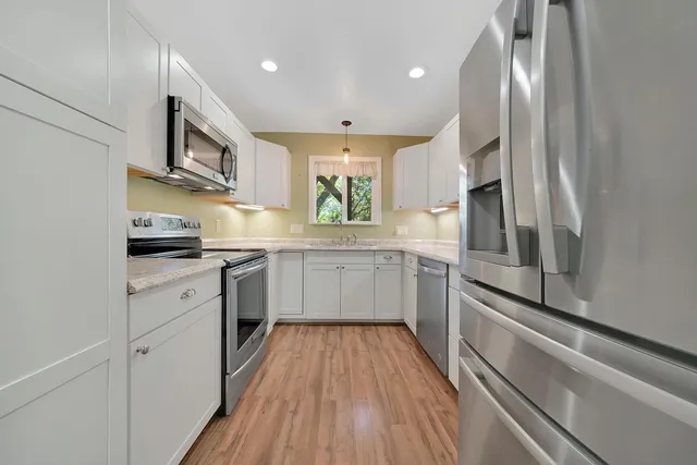 a kitchen with stainless steel appliances a refrigerator sink and white cabinets