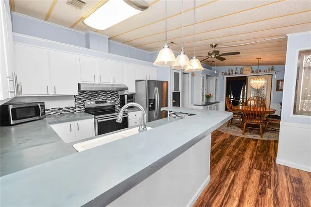a kitchen with stainless steel appliances granite countertop a sink dishwasher and a stove with wooden floor